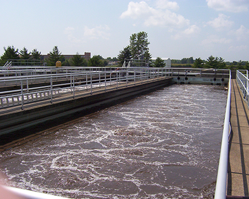 Aeration basin at a wastewater treatment plant, with foaming water between steel walkways